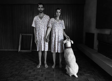 Man, woman, and dog in matching outfits indoors.