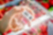 A hand holding a new and empty clamshell of strawberries showing a food traceability label on the bottom of the pack. The label features the farm, variety, pack size, barcode, and QR code
