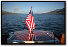 Thumbnail: Hacker-Craft on water up close of aft deck with American flag