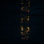 make a dark scene looking down into water seeing only rippled reflections of a golden ambe