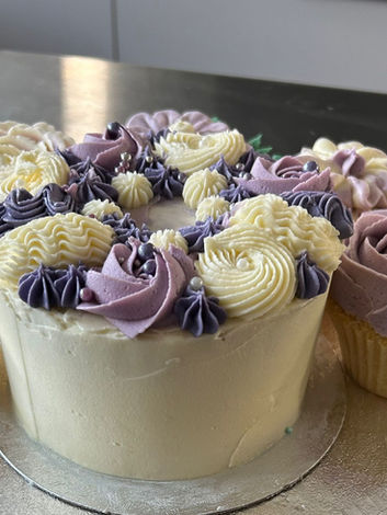 Buttercream celebration cake with five matching cupcakes in coordinating colours, arranged neatly on a cake board.