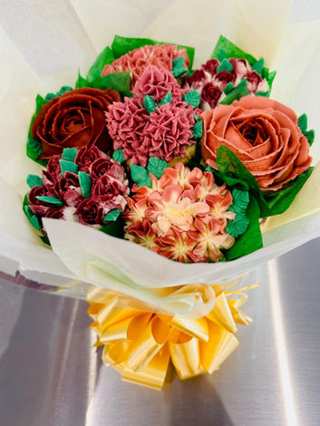 Vibrant red floral cupcake bouquet featuring roses and assorted blooms, presented with a gold ribbon