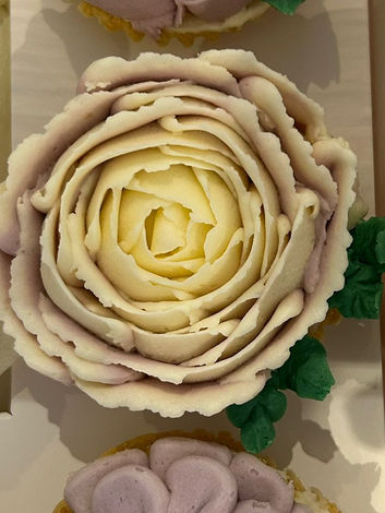 Assortment of 3floral cupcakes decorated in lilac and cream colours.