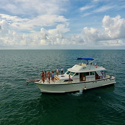Aerial photo of the boat with guests on the bow deck waving helllo.