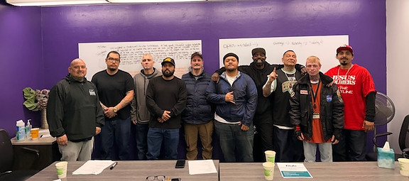 A group of people smiling in front of a whiteboard in a classroom