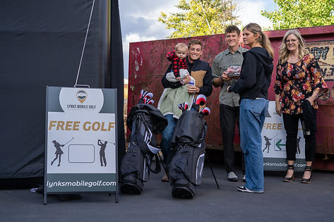 A family smiling around the mobile golf simulator