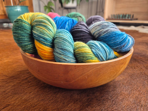 Selection of 8 Ply / DK Weight Yarns in a wooden bowl.