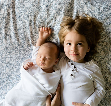 happy siblings- newborn swaddled and asleep, older brother happy