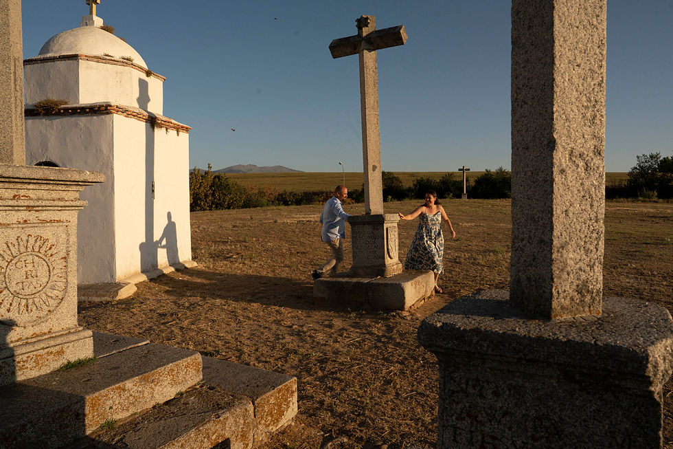 Una pareja de novios corre entre los cruceros de un monumento en medio del campo