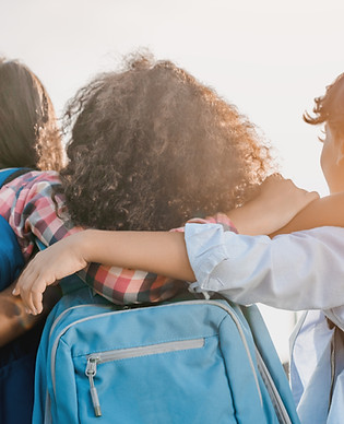 Three students with backpacks, arms around each other