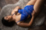 Woman in blue lace lingerie lies on a fur rug, relaxed. Mood is intimate and serene.