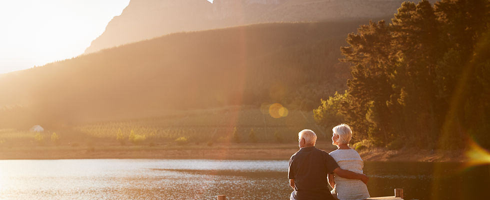 Romantic Senior Couple Sitting On Wooden Jetty By Lake.jpg