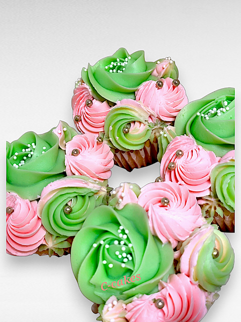 set van cupcakes met crème in de vorm van rozen in groen en roze tinten – cupcakes decorated with rose-shaped cream swirls in green and pink shades