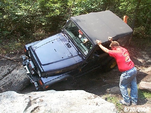 Man assisting Jeep stuck on rocks