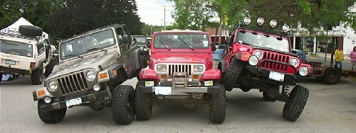 Red Jeep Wrangler flanked by other Jeeps