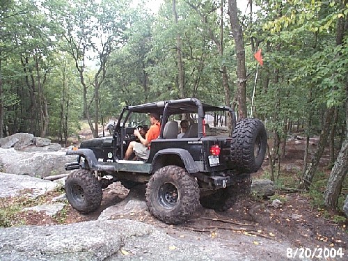 Jeep on rocks, three people inside