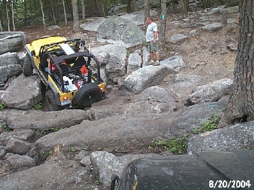 Yellow Jeep navigating rocky terrain