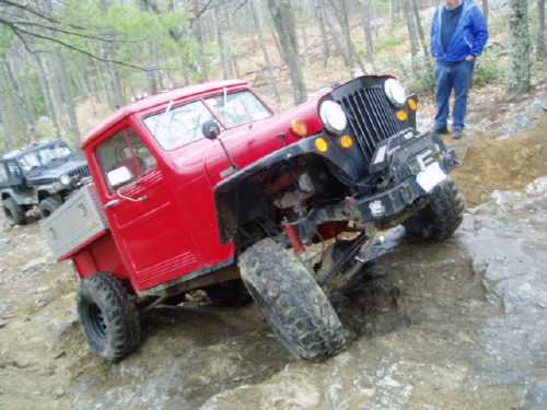 Red Jeep pickup truck off-roading