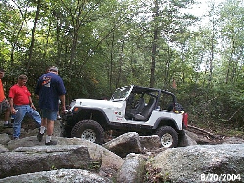 White Jeep navigating rocks, two men watching
