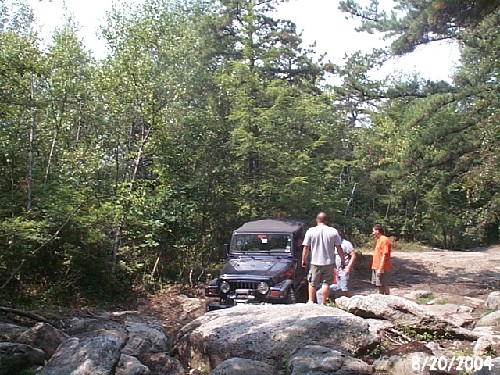 Jeep stuck on rocks; people assisting