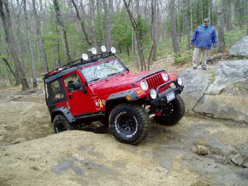 Red Jeep navigating rocky terrain
