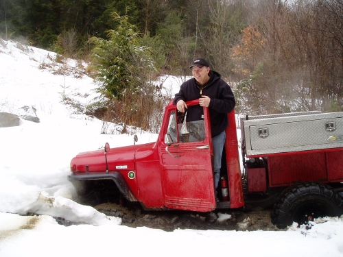 Man standing in red Jeep, snowy landscape