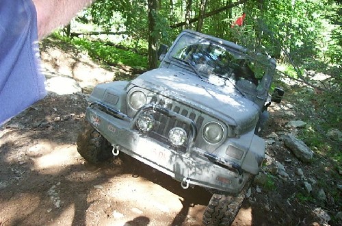 Gray Jeep Wrangler off-roading on a muddy trail