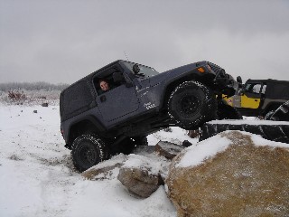 Woman driving Jeep over rocks in snow