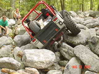 Red Jeep navigating rocky terrain during off-road trail ride