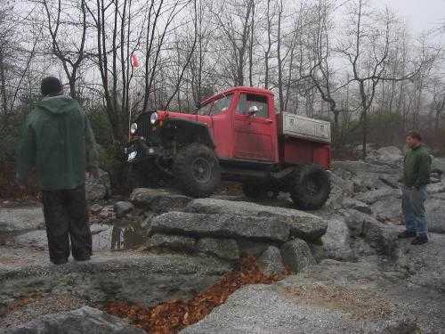 Red Jeep truck navigating rocky terrain