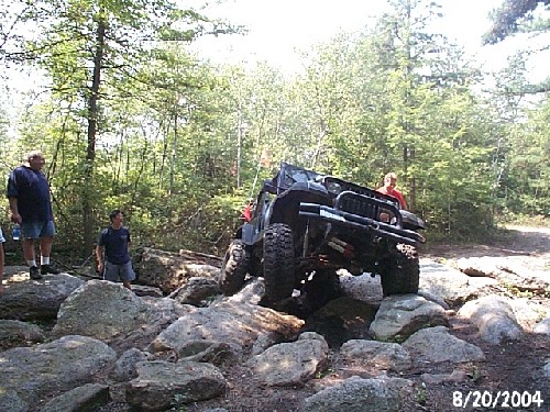 Jeep navigating rocks, two men watching