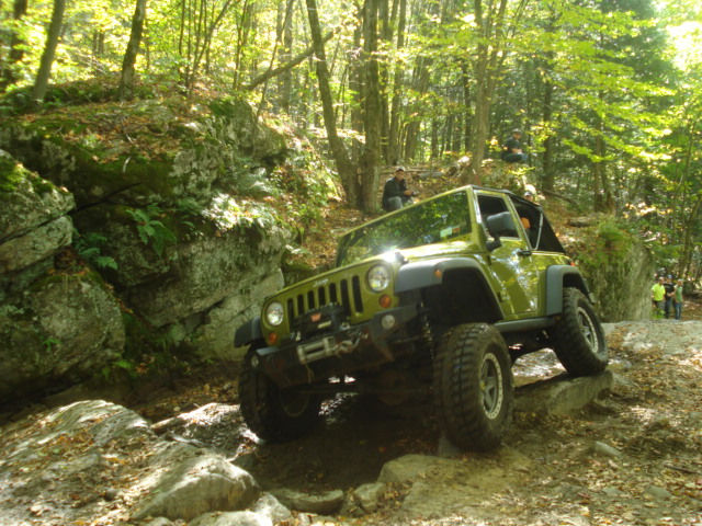 Green Jeep navigating rocky trail