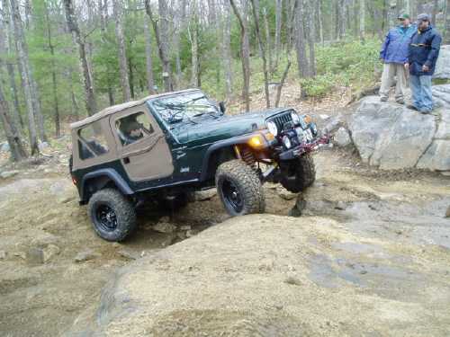 Green Jeep navigating rocky terrain