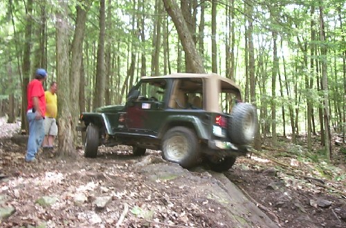 Jeep traversing rocky trail, onlookers watching