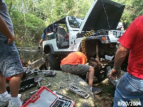 Jeep repair in woods; mechanics work on lifted vehicle