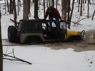 Person climbing onto a Jeep stuck in snow
