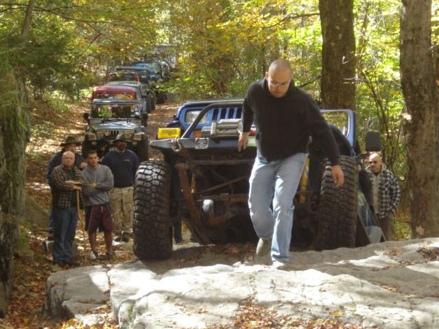 Man assisting Jeep on rocky trail, off-roading group