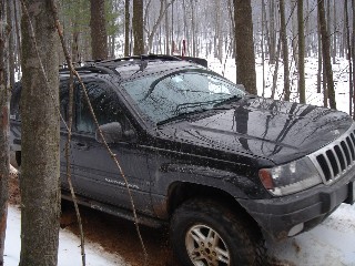 Black Jeep Grand Cherokee in snowy woods