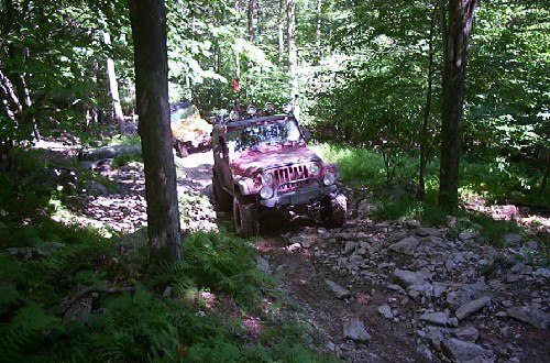 Red Jeep navigating rocky trail, Long Island Off Road