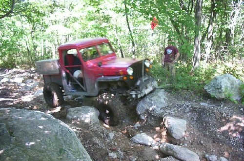 Red Jeep navigating rocky terrain