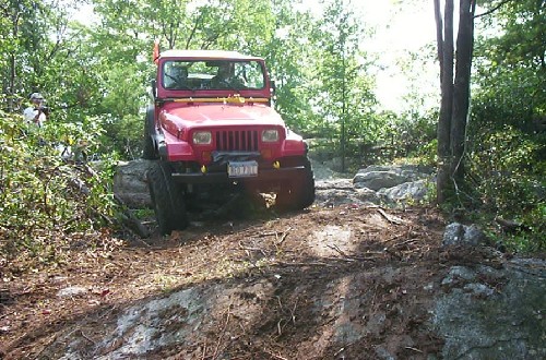 Red Jeep navigating rocky terrain