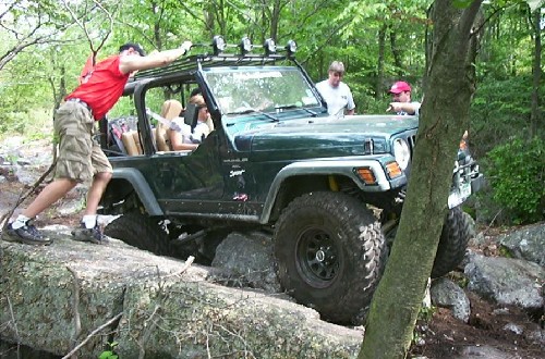Jeep navigating rocks, people assisting