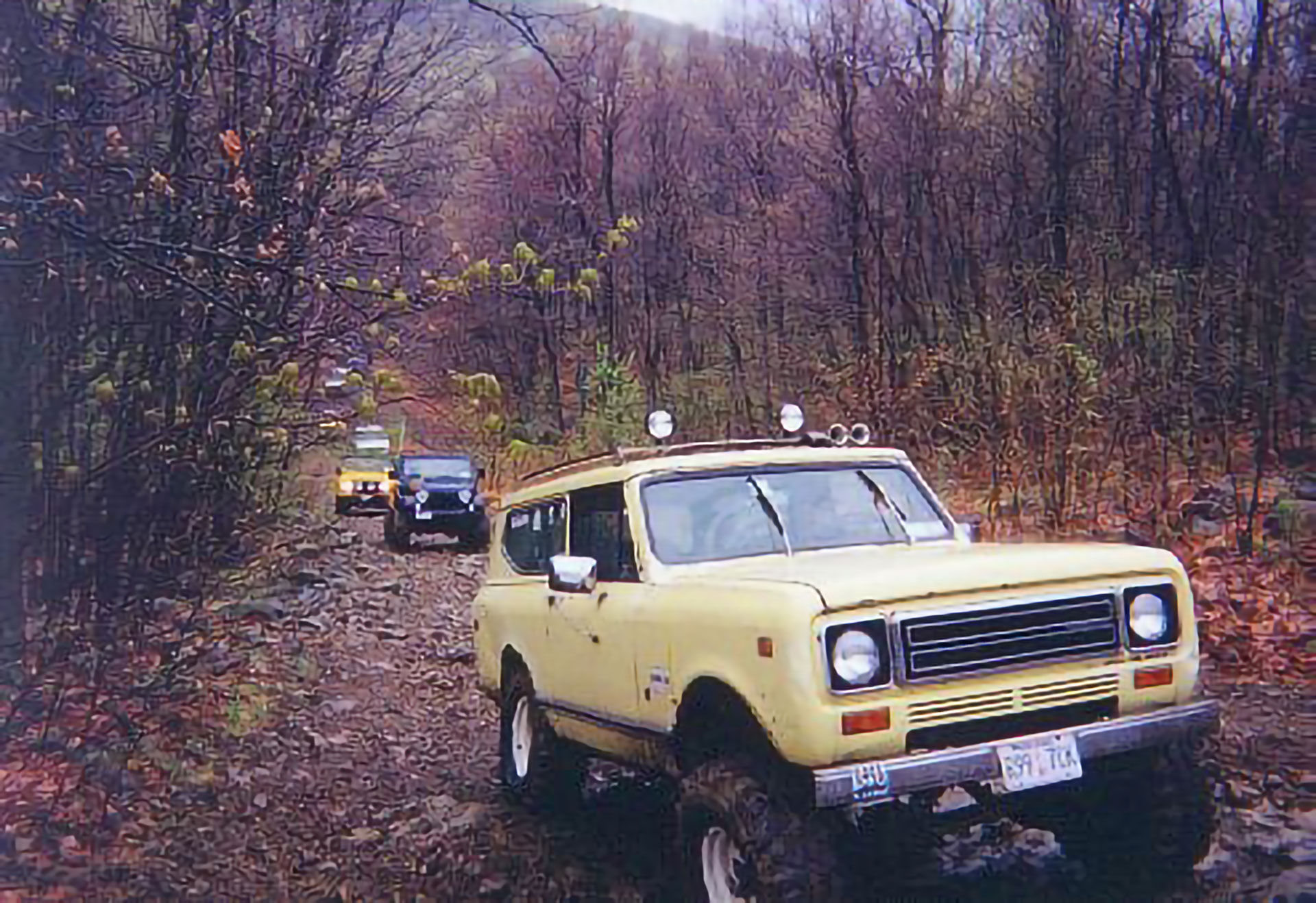 Yellow International Scout off-roading on muddy trail