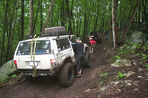 Off-roaders assisting Jeep in wooded trail