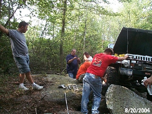 Men fixing Jeep on rocks