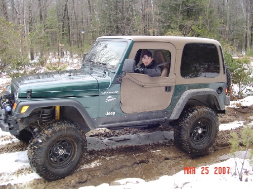Man in green Jeep Wrangler off-road