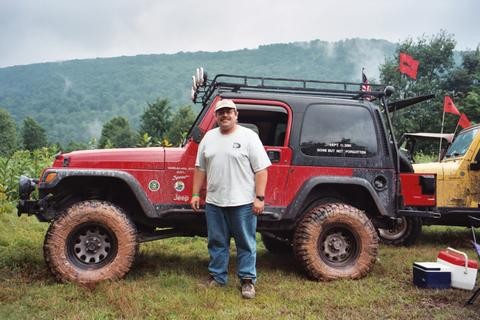 Man standing beside muddy Jeep, Long Island Off Road