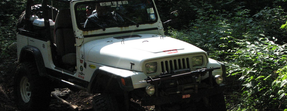 White Jeep traversing a muddy trail