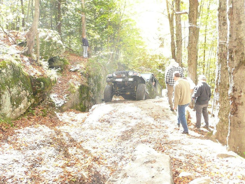Off-road Jeep ascending rocky trail; spectators watching
