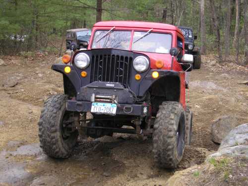 Red Jeep traversing muddy trail